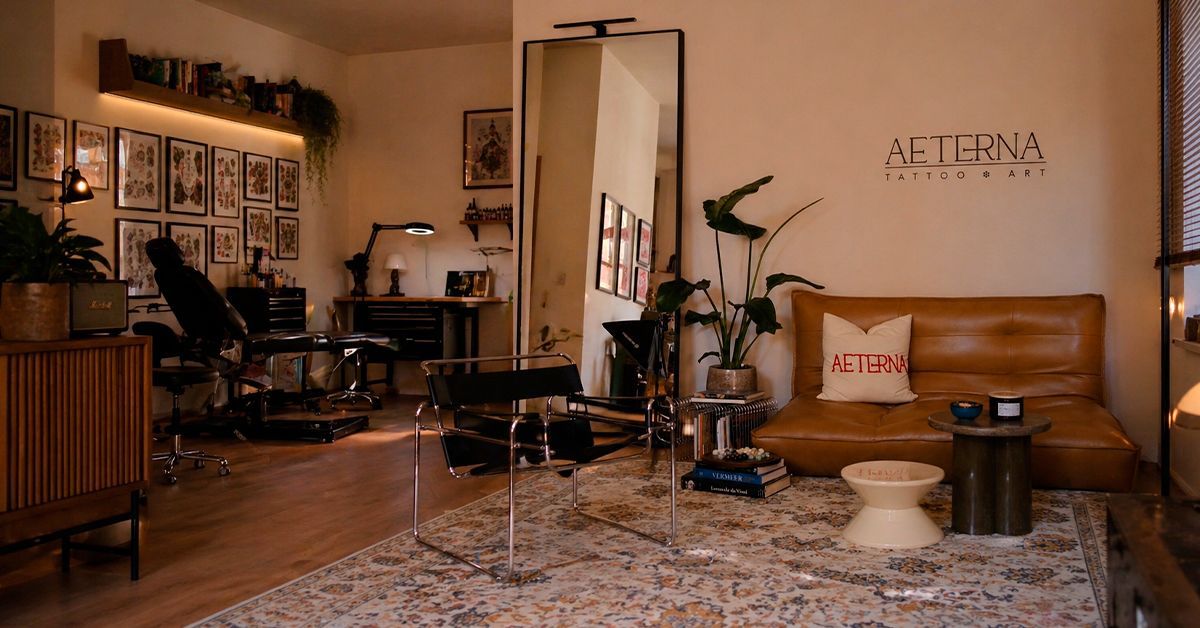 ÆTERNA Tattoo Studio in Köln-Mülheim – Innenansicht mit Couch, Logo und Arbeitsplatz